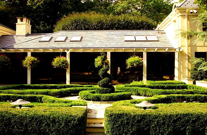 A large house with a lush green garden in front of it