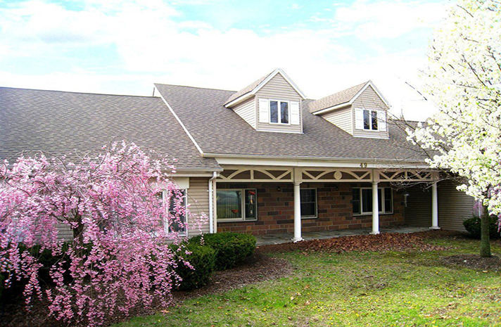 A house with a porch and pink flowers in front of it