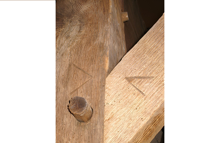 A close up of a wooden beam with a triangle carved into it.