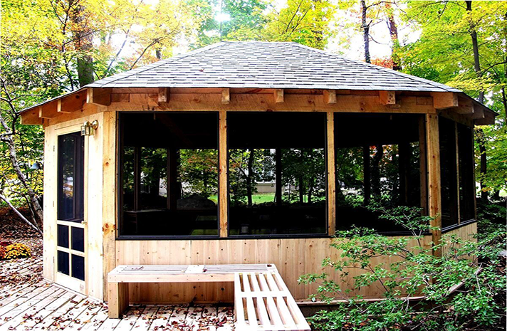 A screened in gazebo with a bench in front of it