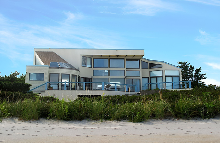 A large house is sitting on top of a sandy beach.