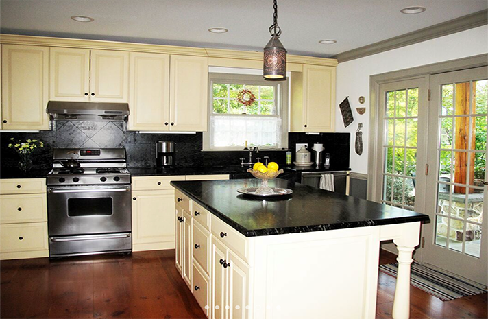 A kitchen with white cabinets and black counter tops