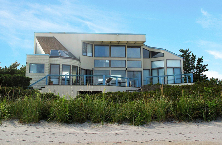 A large house is sitting on top of a sand dune.