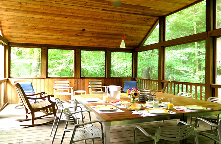 A screened in porch with a table and chairs