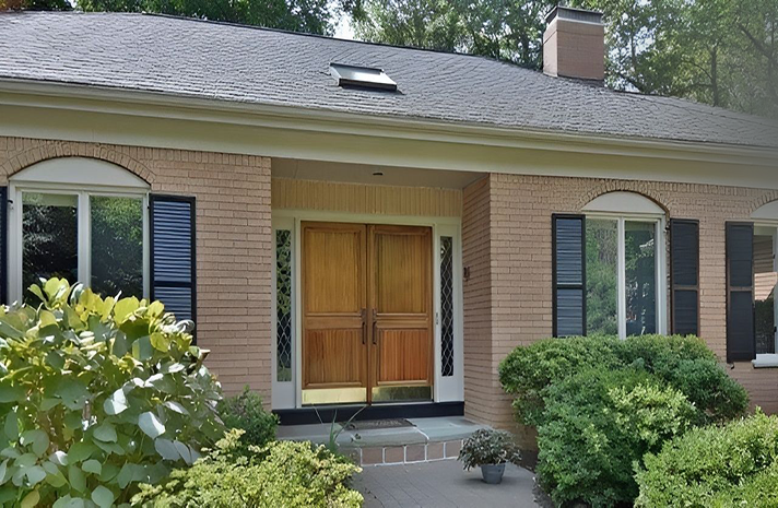 A brick house with a wooden door and black shutters