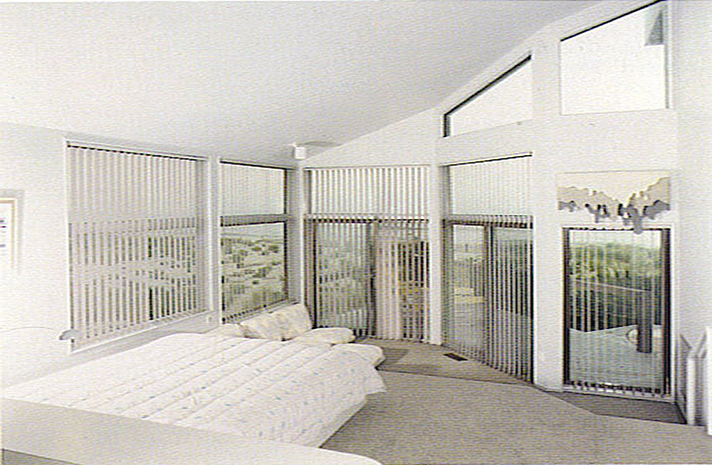 A bedroom with a large bed and lots of windows