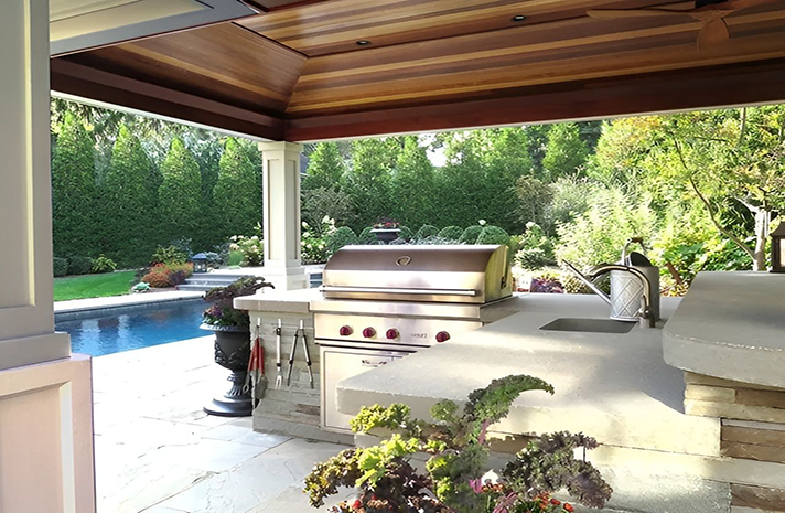 A large outdoor kitchen with a grill and a sink