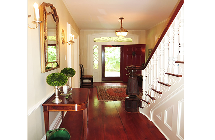 A hallway with stairs and a mirror on the wall