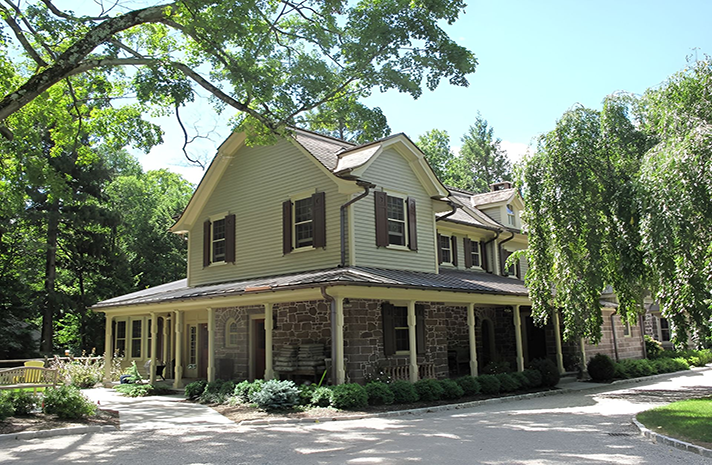 A large house with a porch and trees in the background