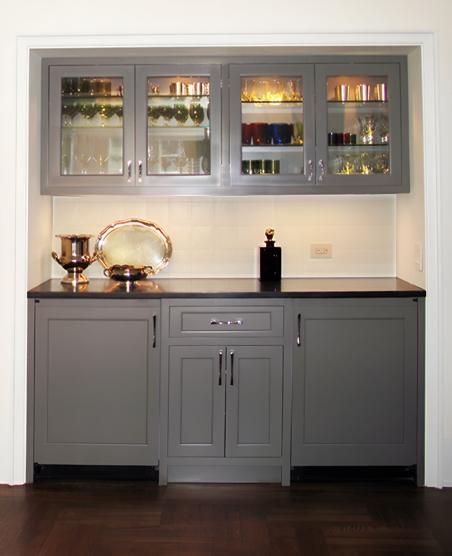A kitchen with gray cabinets and glass doors
