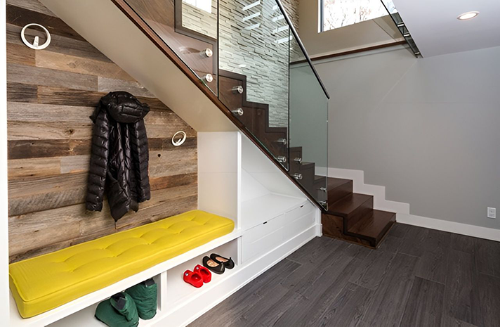 A coat is hanging on a wall in a hallway under a staircase.