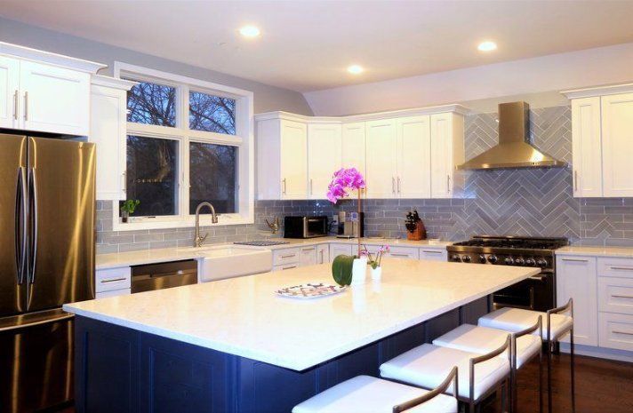 A kitchen with white cabinets , stainless steel appliances and a large island.