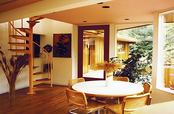 A dining room with a table and chairs and a spiral staircase