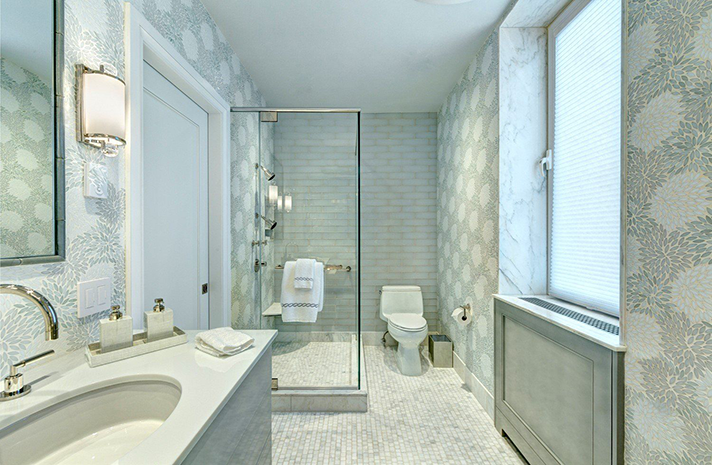 A bathroom with a toilet , sink , mirror and walk in shower.