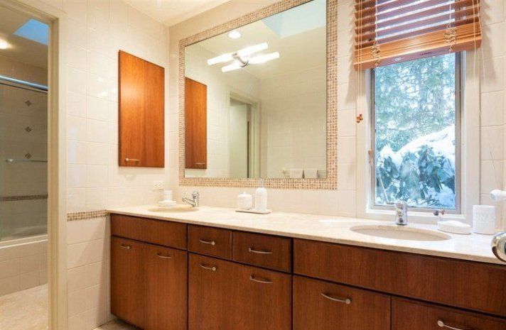 A bathroom with two sinks , a large mirror and a window.