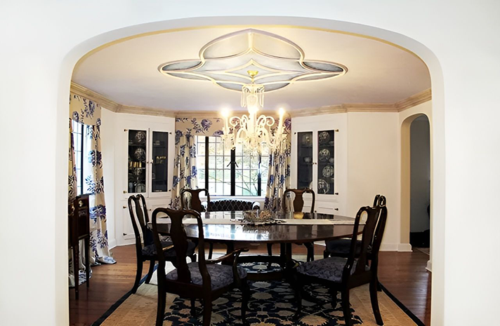 A dining room with a table and chairs and a chandelier hanging from the ceiling.