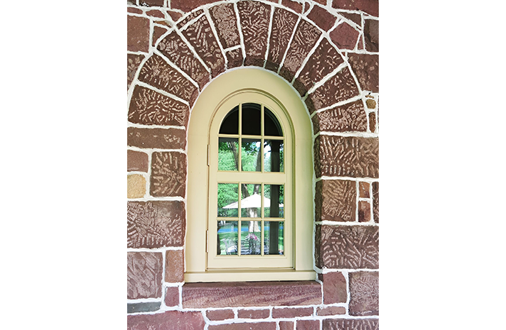 A brick wall with a window in the middle of it