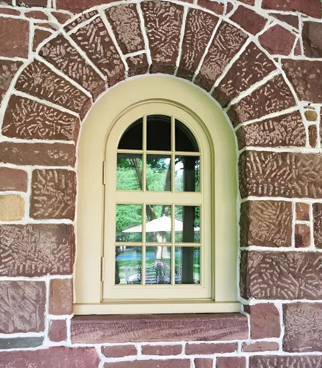 A brick wall with a window in the middle of it