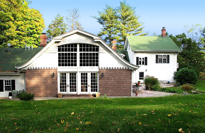 A white house with a green roof is next to a brick house