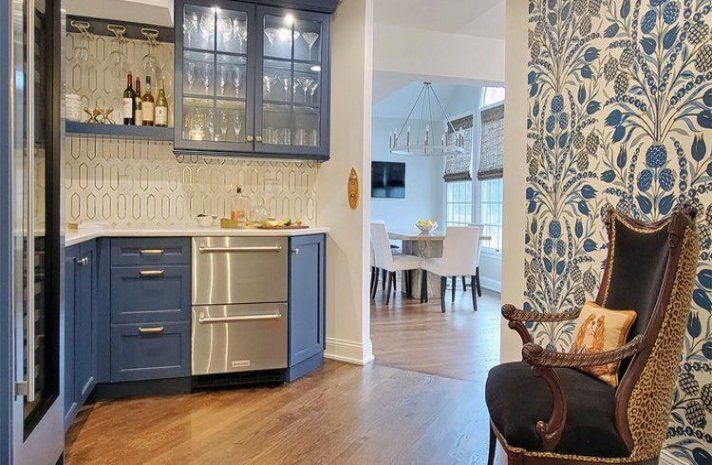 A kitchen with blue cabinets , stainless steel appliances , and a chair.