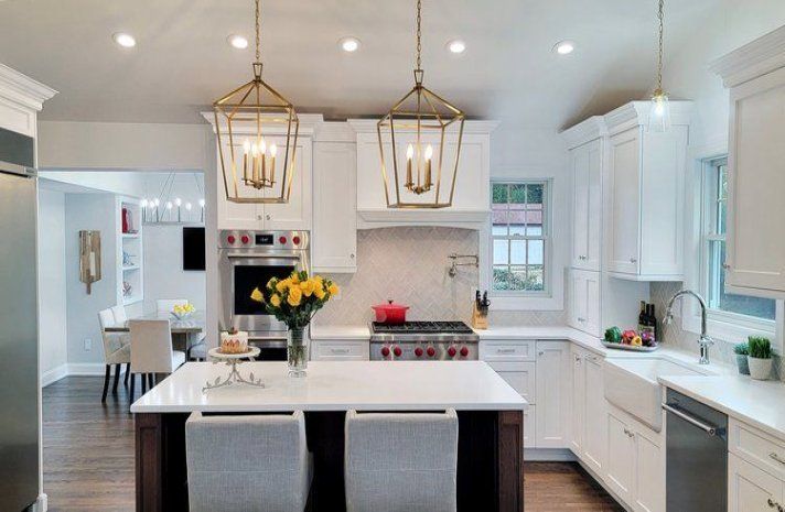 A kitchen with white cabinets , stainless steel appliances , and a large island.