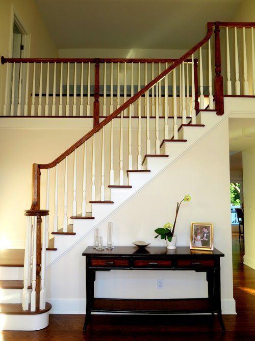 A staircase with a wooden railing and a table underneath it