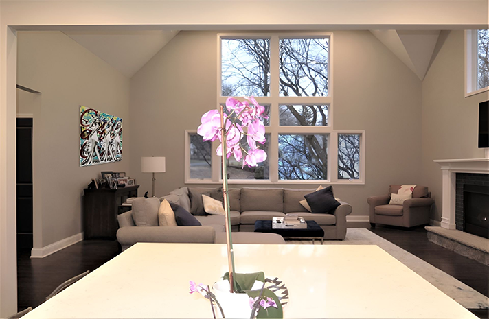 A living room with a couch and a fireplace and a vase of flowers on the table