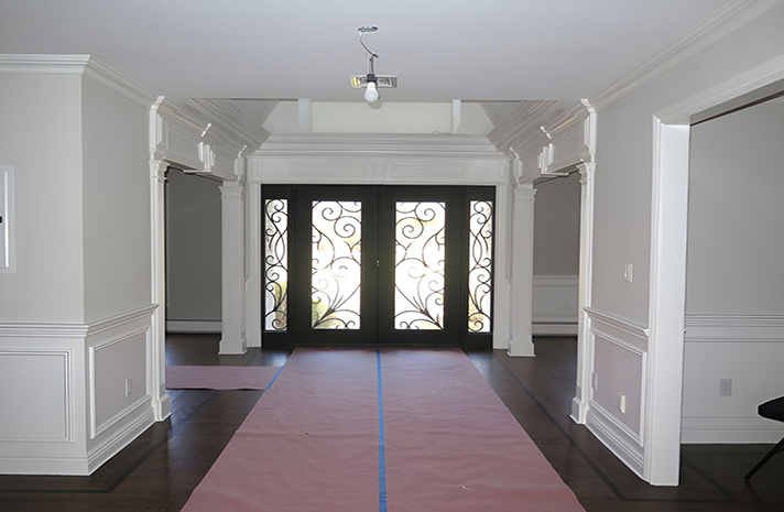 A hallway with a pink carpet and a wrought iron door