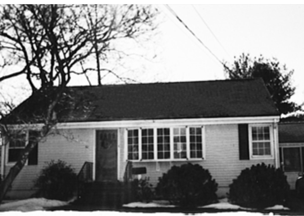 A black and white photo of a house with a black roof