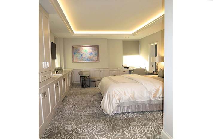 A bedroom with a large bed , a desk , and a painting on the wall.