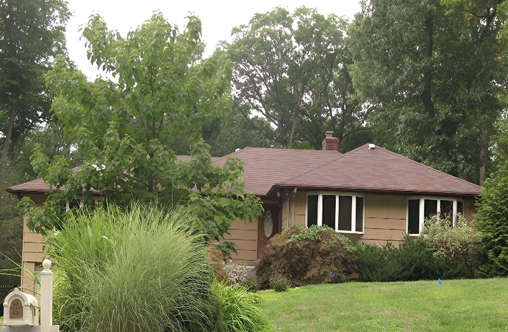 A house with a red roof is surrounded by trees and grass