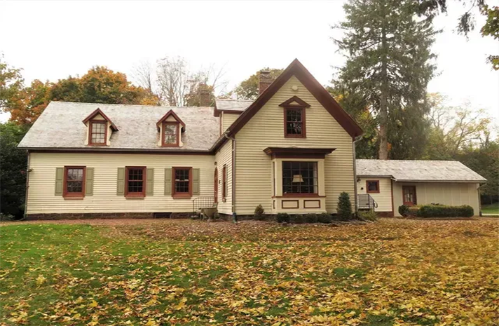 A house with a lot of leaves on the ground in front of it