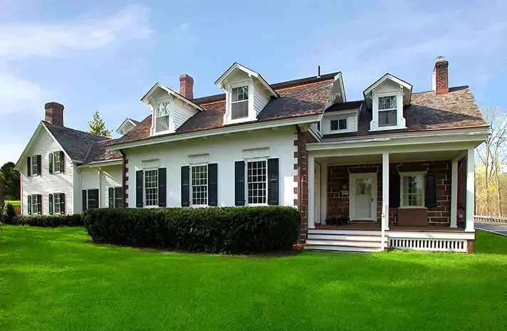A large white house with black shutters and a porch