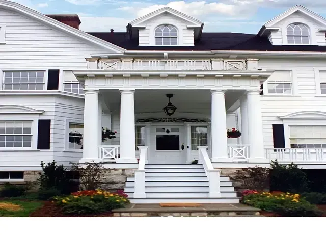 A large white house with a porch and stairs