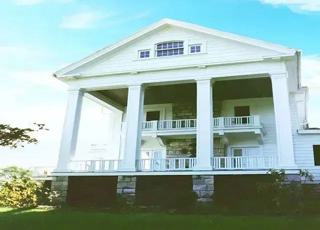 A large white house with columns and balconies on a sunny day