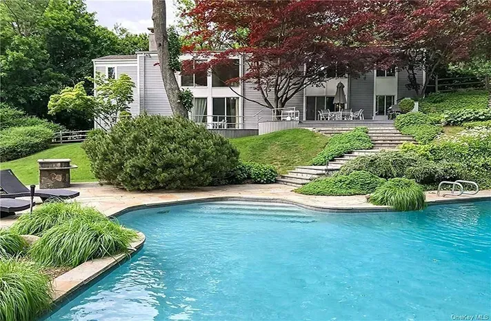 A large swimming pool is in the backyard of a house.