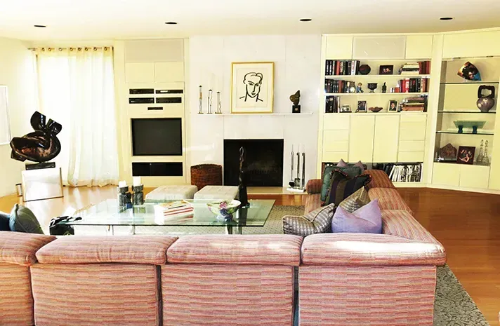 A living room with a pink couch and a fireplace