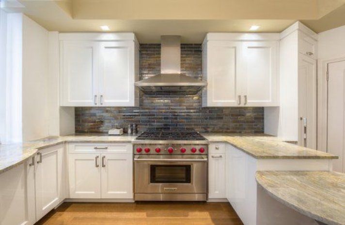 A kitchen with white cabinets , stainless steel appliances and granite counter tops.