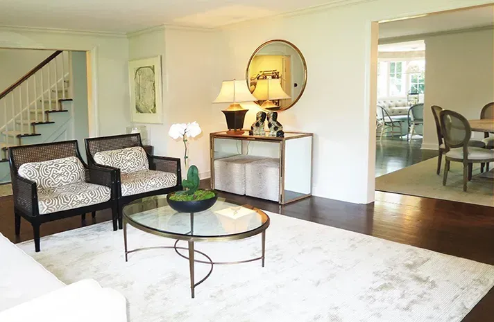 A living room with a couch , chairs , a coffee table and a mirror.