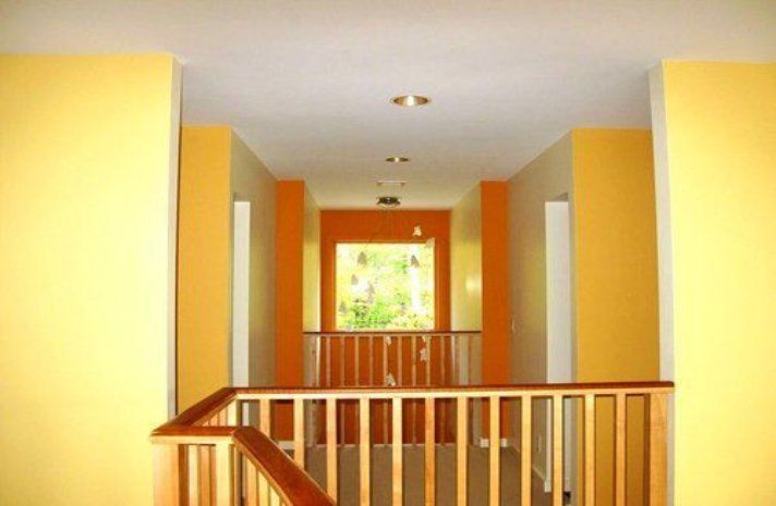 A hallway with yellow walls and a wooden railing