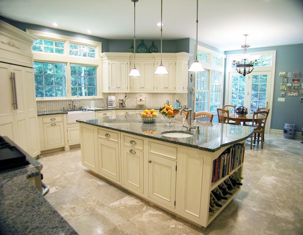 A kitchen with white cabinets and a large island in the middle