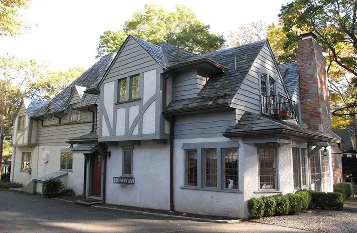 A white and gray house with a brick chimney on the roof.