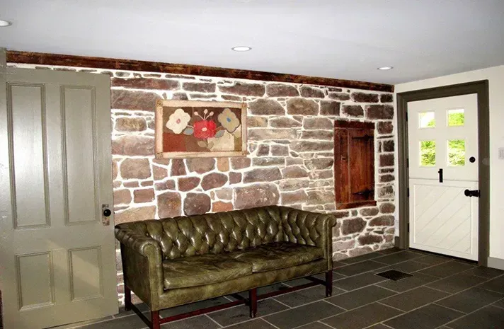 A living room with a couch and a stone wall