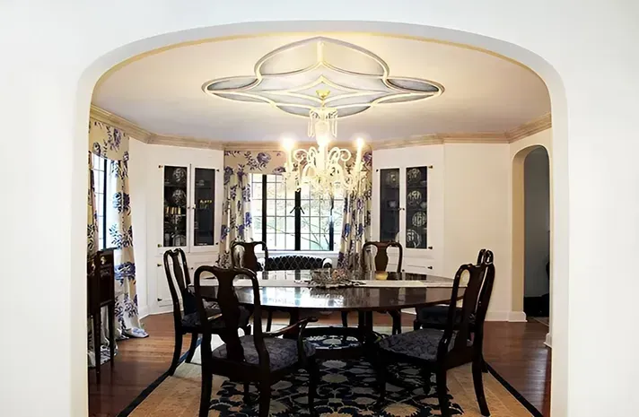 A dining room with a table and chairs and a chandelier hanging from the ceiling.