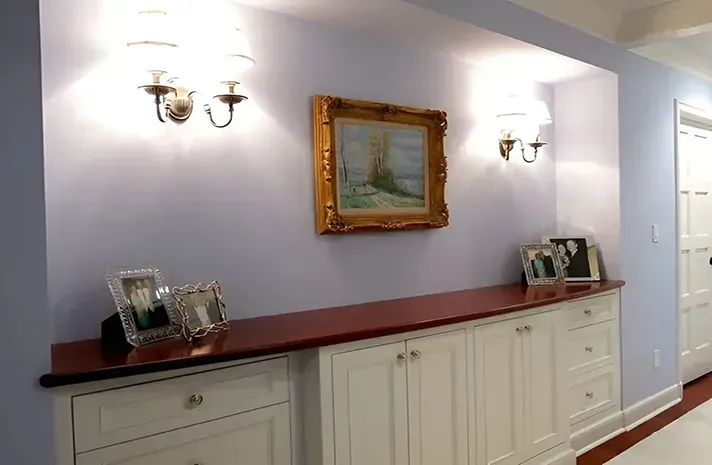 A hallway with a painting on the wall above a dresser.