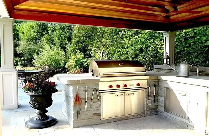 An outdoor kitchen with a grill and a sink under a canopy.