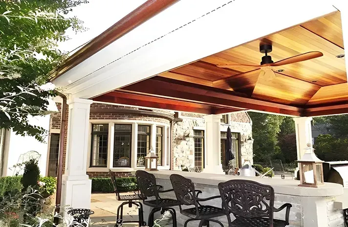 A covered patio with a ceiling fan and chairs