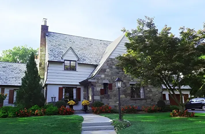 A white house with a stone roof and a walkway leading to it