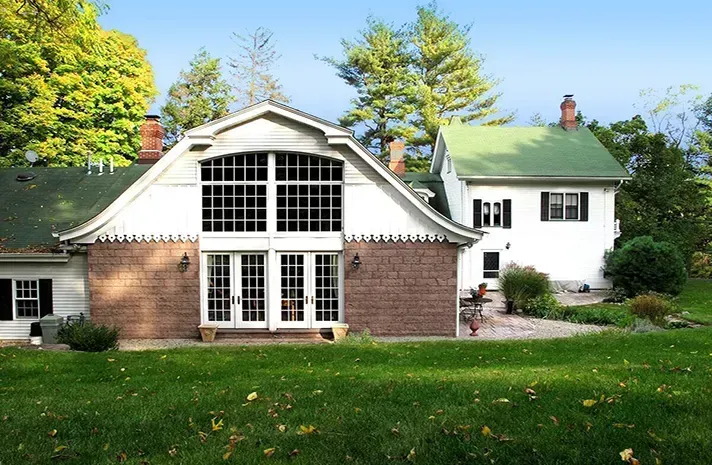 A white house with a green roof sits next to a brick house