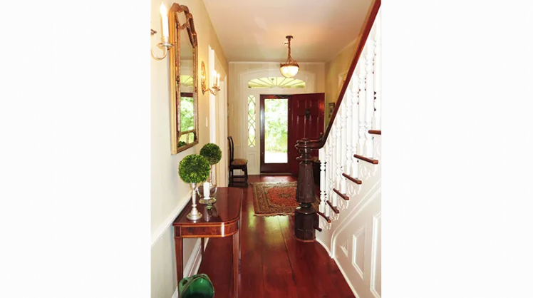A hallway with stairs and a table in the middle